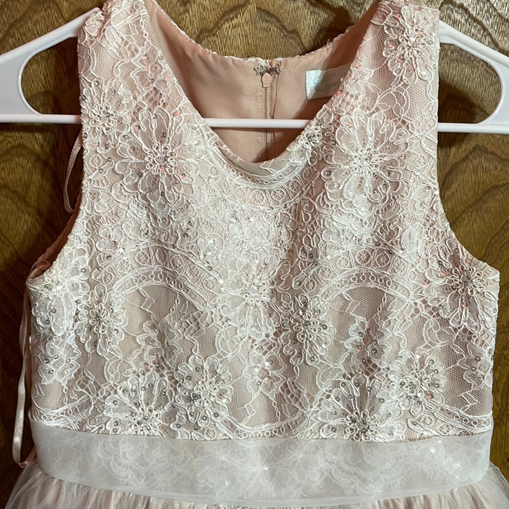 The color of this dress is light pink. It has a lace top with sparkles.